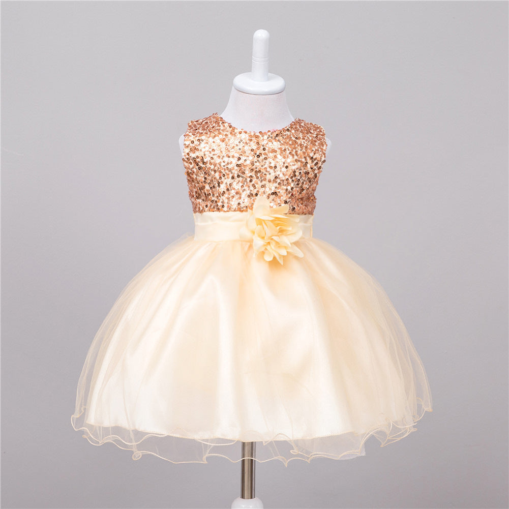Champagne baby dress featuring a rose gold sequined bodice, satin waist, and full tulle skirt with a floral accent.