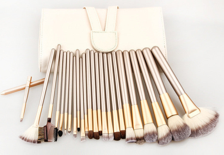 Set of 24 champagne-gold makeup brushes with soft bristles and a matching portable white roll-up storage case.