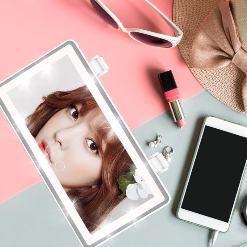 Rectangular white LED car sun visor mirror with touch controls, surrounded by fashion accessories on a two-tone surface.