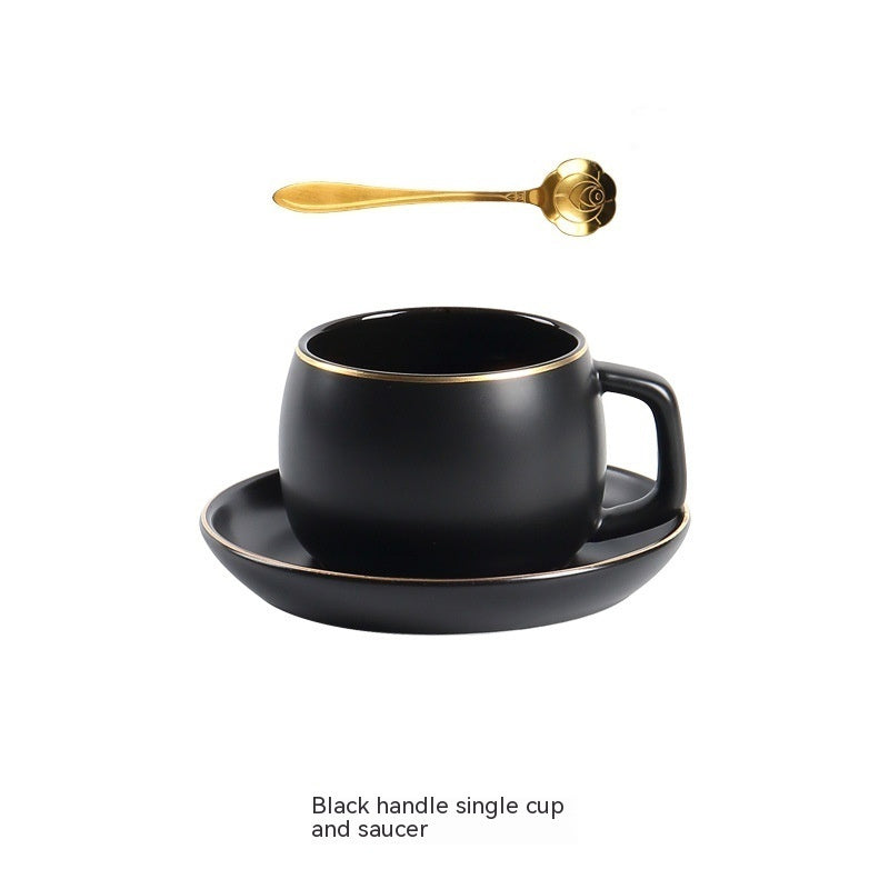 Matte black ceramic coffee cup and saucer set with gold rim detailing and a decorative gold rose-shaped spoon.