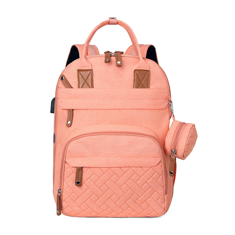 Peach-colored multi-functional diaper backpack with brown accents, front quilted pattern, and side USB port.
