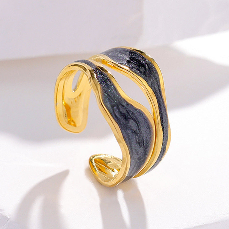 Open-toed golden titanium steel ring with an abstract, wavy black enamel inlay on a white background.
