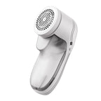 A handheld white lint remover with a circular mesh head and a translucent detachable lint collection compartment.