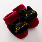 Soft red and black baby socks featuring plush 3D black cat faces with yellow embroidered eyes and whiskers.