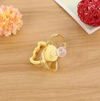 A clear, yellow-tinted silicone baby pacifier with a round nipple, resting on a wooden surface with decorative flowers.