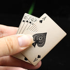 A hand holds a metallic gold playing card-shaped windproof lighter featuring intricate black spade and royal card designs.