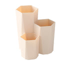 Beige, hexagonal, three-tiered plastic makeup brush holder with a geometric design, isolated on a white background.
