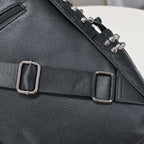 Black pebble-grain leather backpack with silver metal studs, adjustable fabric strap, and metal buckles.