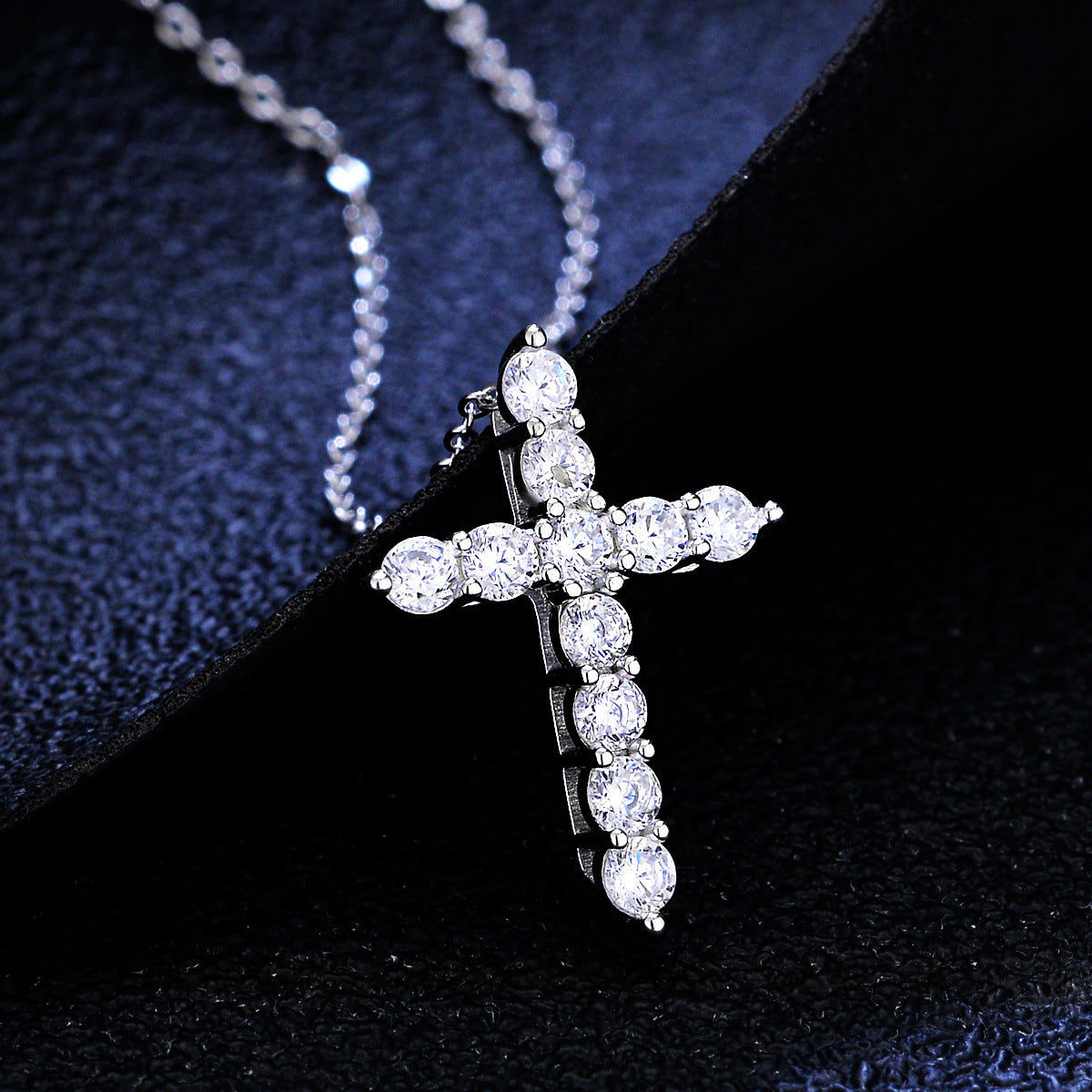 Silver-tone cross pendant necklace set with clear, round-cut sparkling stones on a delicate matching chain.