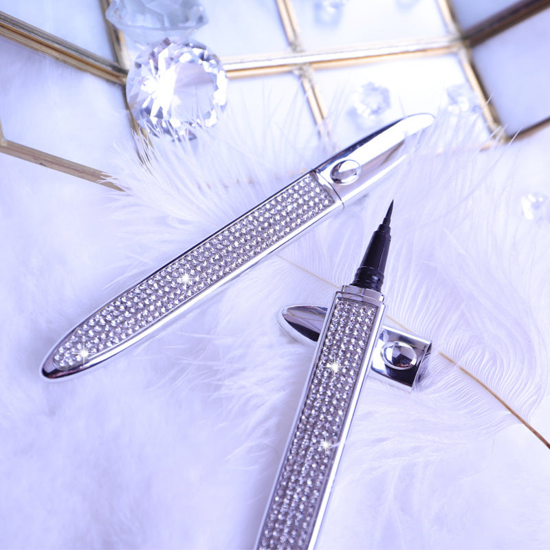 Rhinestone-encrusted self-adhesive eyeliner pens with fine tips on a white feather background with crystal accents.