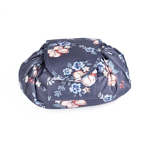 A dark grey, round, drawstring-style cosmetic bag with a pink and light blue floral pattern, closed with a front flap.