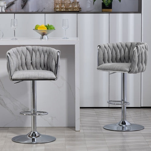 Two gray fabric swivel bar stools with woven backrests, chrome pedestals, and footrests by a white kitchen island.