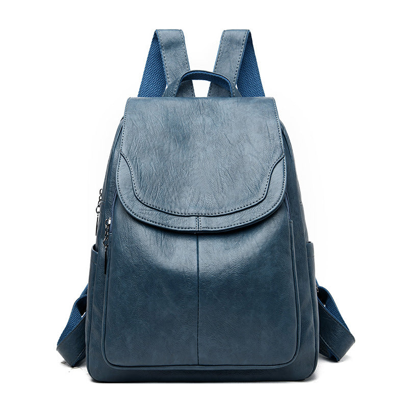 Blue soft leather backpack with a flap top, adjustable fabric straps, and side pockets against a white background.