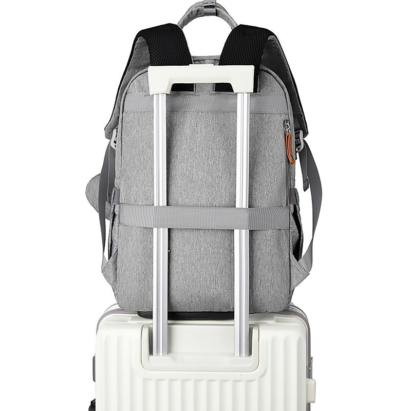 Grey fabric travel backpack with luggage strap, black padded straps, and zipper detail, mounted on a white suitcase.