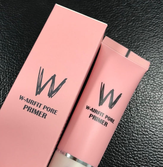 Pink W-Airfit Pore Primer tube and matching box with black logo text, set against a black textured background.