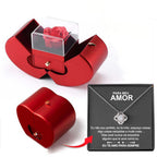 Red heart-shaped jewelry box with an eternal red rose, pull-out drawer, and a silver necklace on a Portuguese note card.