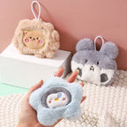 Three plush mini hand warmers featuring embroidered animal faces in beige, grey, and blue, each with a hanging loop.