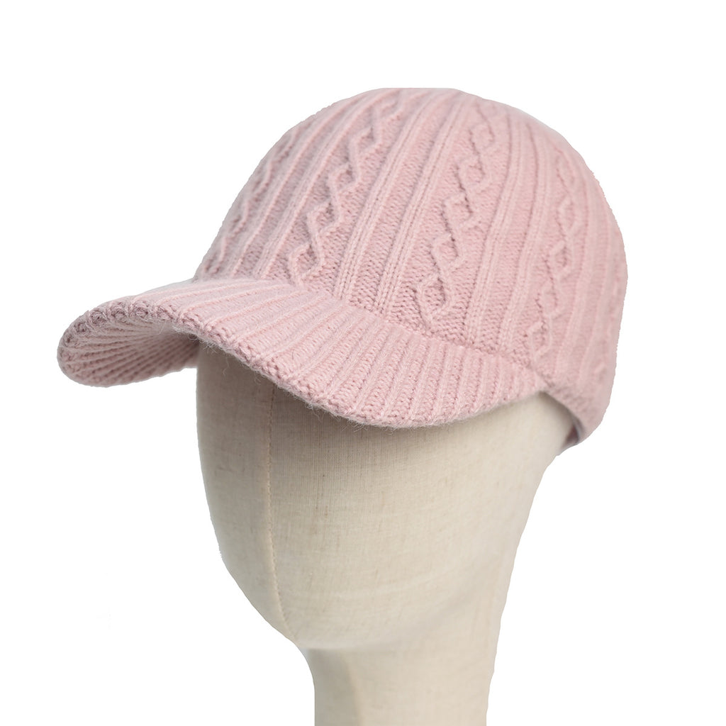 A light pink, cable-knit wool baseball cap on a mannequin head, featuring a solid color and a matching brim.