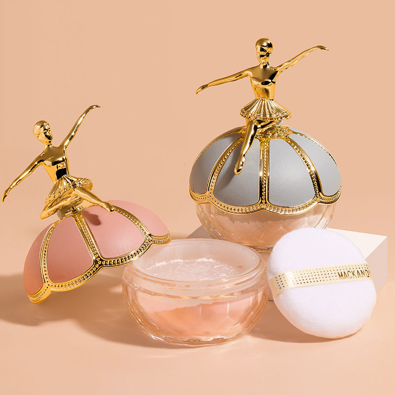 Two Maco Andy ballerina-topped powder jars in pink and grey, with a clear powder base and soft white puff applicator.