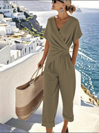 A woman wears an olive green, V-neck, short-sleeved wrap-style top and matching cuffed cropped trousers set.