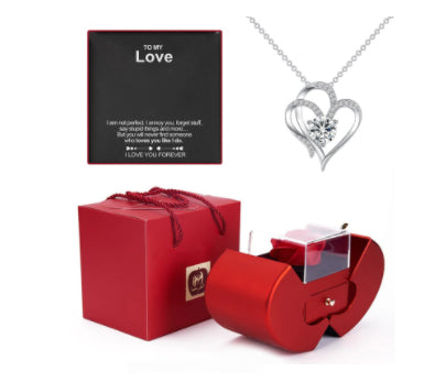 Red apple-shaped jewelry box with artificial rose, heart pendant necklace, and "To My Love" message card.