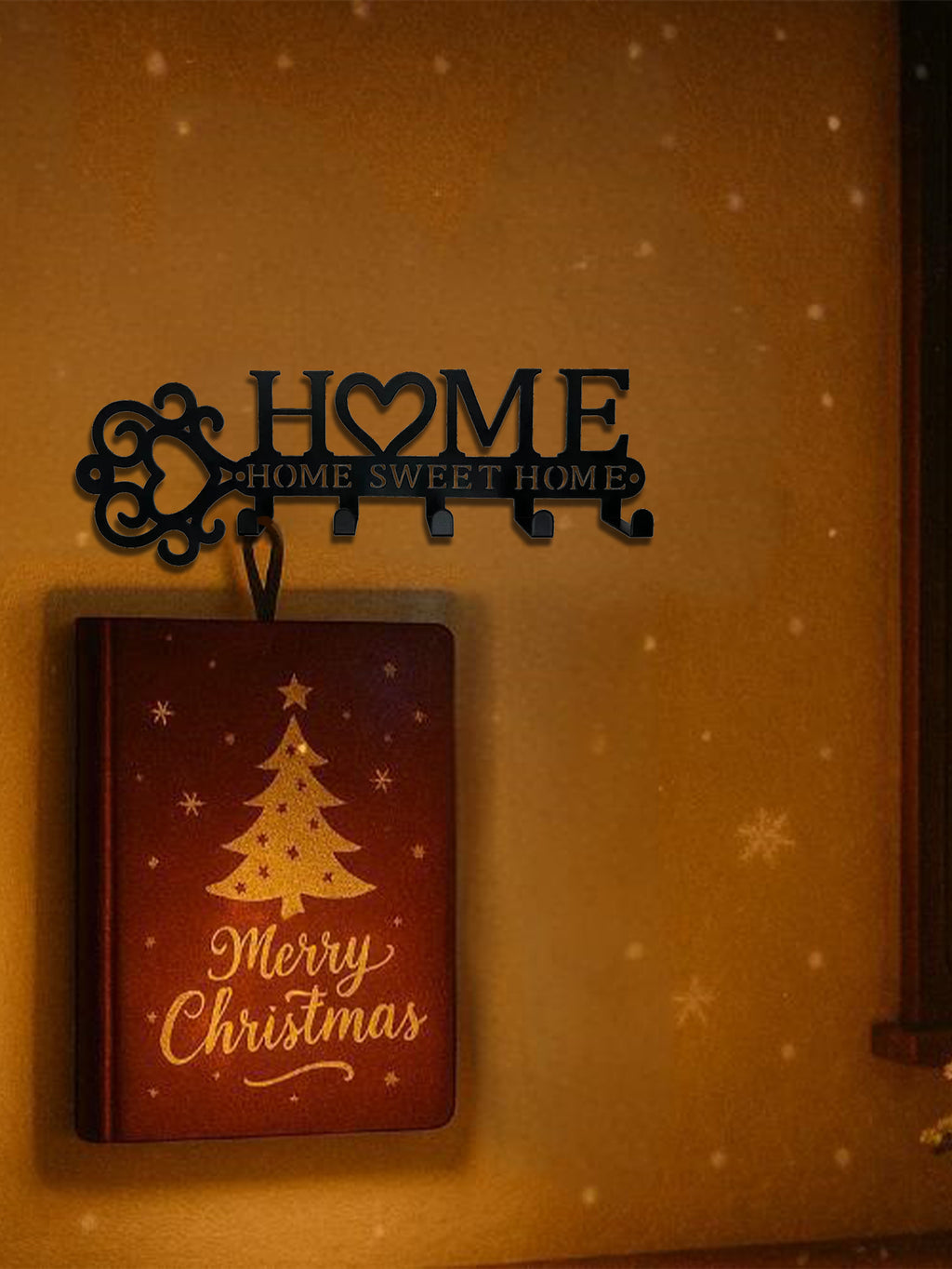 Black metal wall hook featuring a key-shaped design with a heart "O" and "HOME SWEET HOME" text, holding a Christmas book.