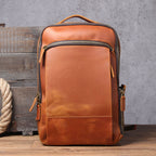 Tan leather vintage-style backpack with bronze zippers, a top handle, and a slim, minimalist silhouette.