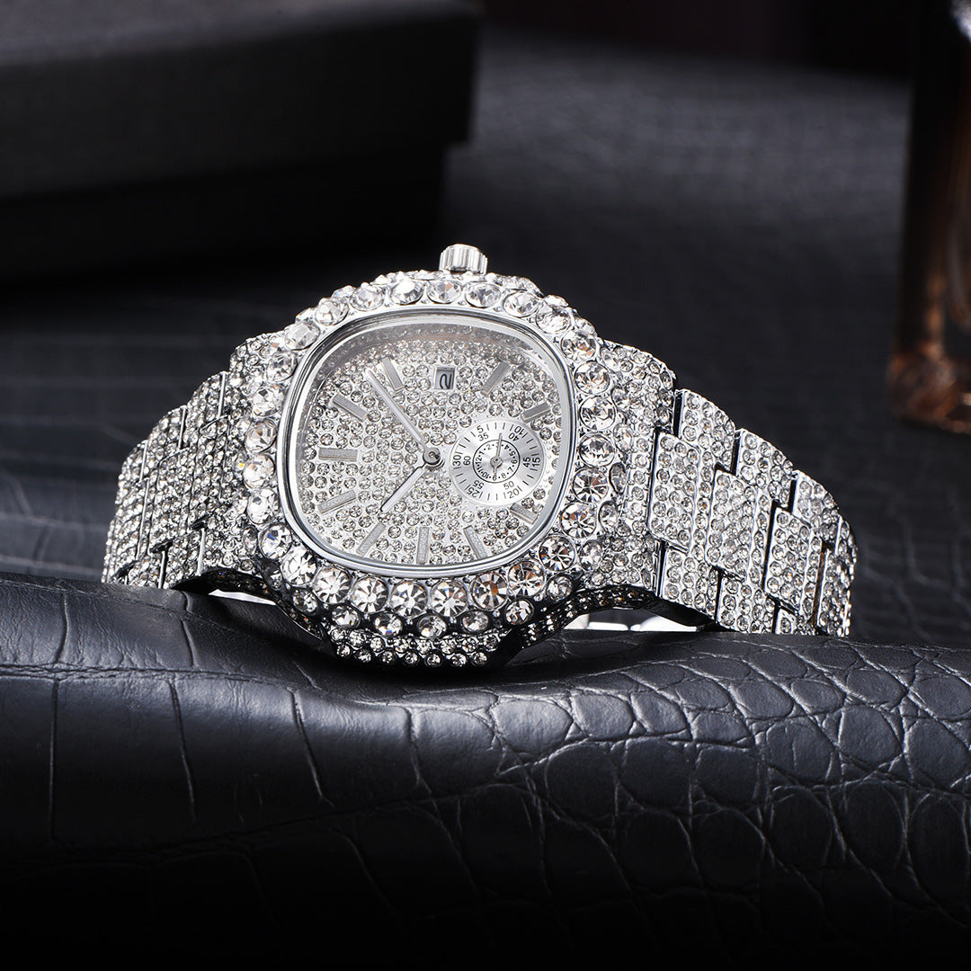 Iced-out silver-tone men's quartz watch fully encrusted with shimmering rhinestones on a textured black leather surface.