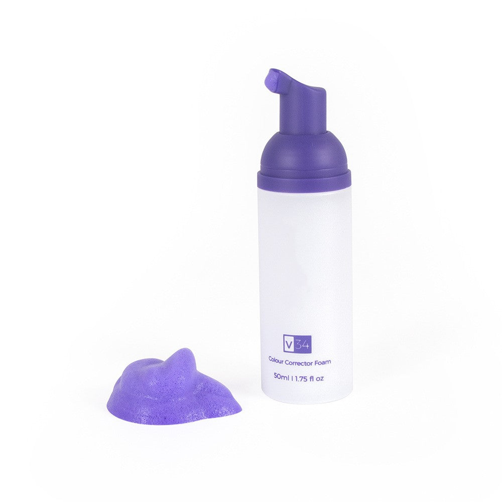 A white pump bottle of V34 purple teeth whitening foam next to a dollop of purple mousse on a white background.