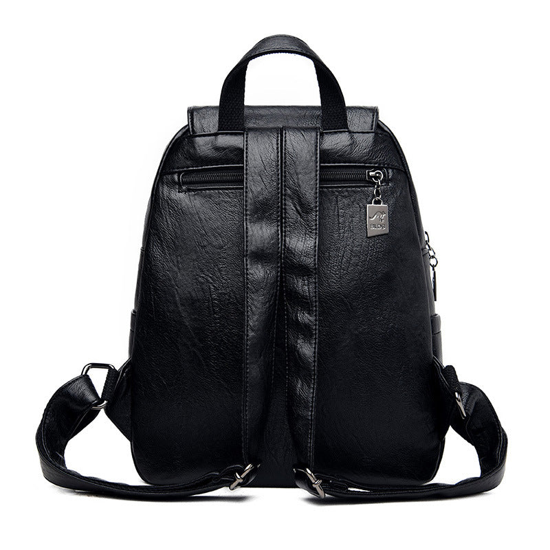 Black faux leather backpack with adjustable straps, top handle, zippered back pocket, and metallic brand charm.