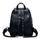 Black faux leather backpack with adjustable straps, top handle, zippered back pocket, and metallic brand charm.