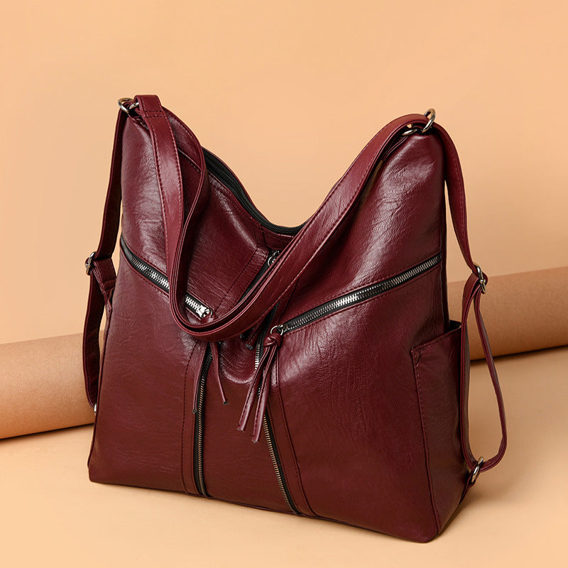 Burgundy soft leather convertible shoulder bag and backpack with silver zippered pockets and adjustable straps.