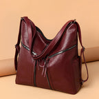 Burgundy soft leather convertible shoulder bag and backpack with silver zippered pockets and adjustable straps.