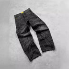 Black denim jeans with distressed flame-shaped patchwork patterns, relaxed fit, and frayed raw hem edges.