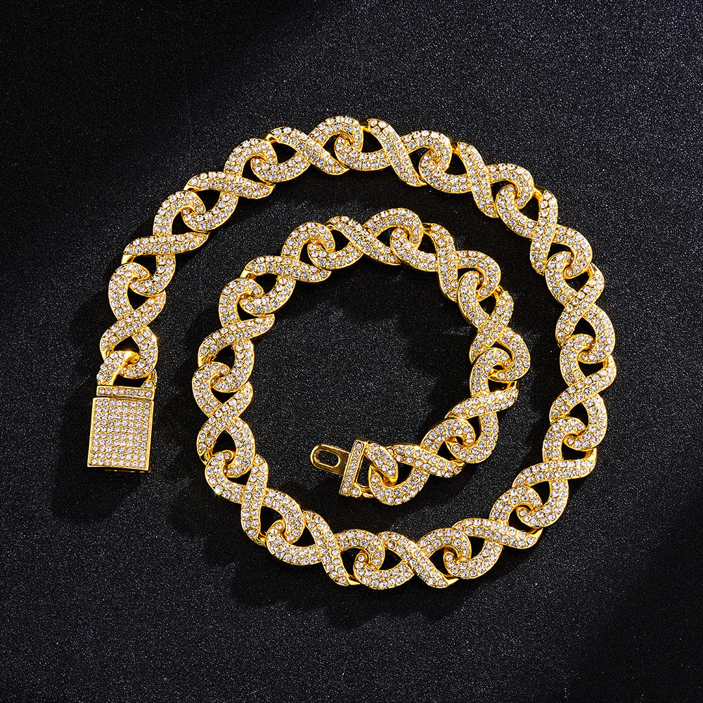 Gold-tone hip hop chain with an infinity-link design, fully encrusted in clear sparkling crystals on a black background.