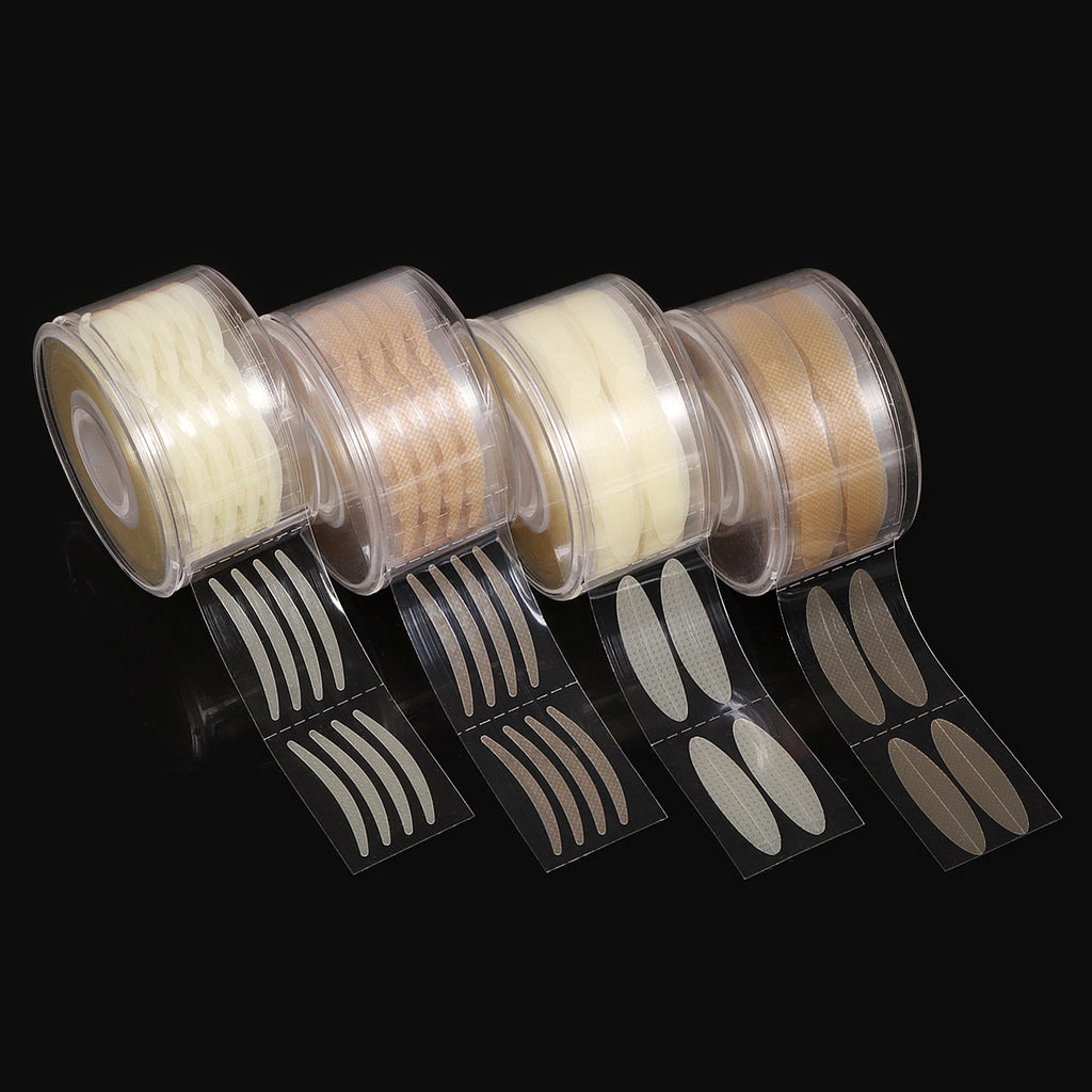 Four clear plastic rolls of beige and transparent adhesive eyelid stickers in various shapes on a black background.