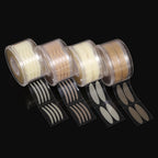 Four clear plastic rolls of beige and transparent adhesive eyelid stickers in various shapes on a black background.