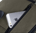 Olive green canvas backpack with a zippered front pocket holding a silver smartphone.