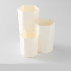 Off-white, hexagonal plastic makeup brush organizer with three staggered compartments of varying heights.