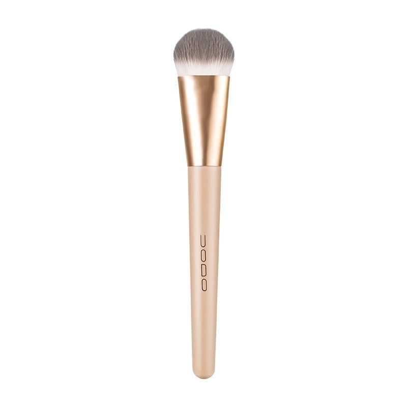 Flat-head makeup brush with soft grey/white synthetic bristles, gold ferrule, and matte beige handle.