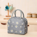 Gray insulated lunch bag with daisy print, durable fabric, zip closure, and dual carrying handles on a kitchen table.