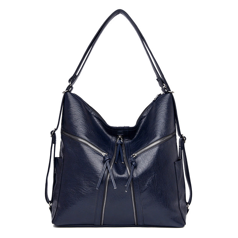 A navy blue, soft leather multifunctional shoulder bag and backpack with two prominent front zipper pockets.