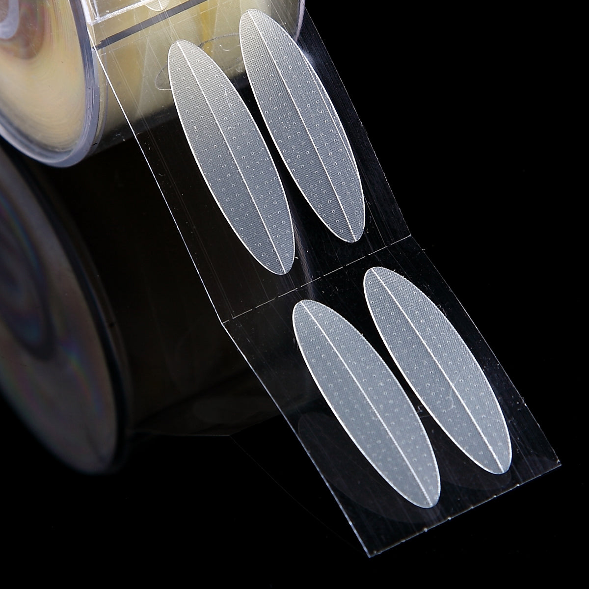 Clear, beige textured adhesive eyelid strips on a transparent roll for creating double eyelids.