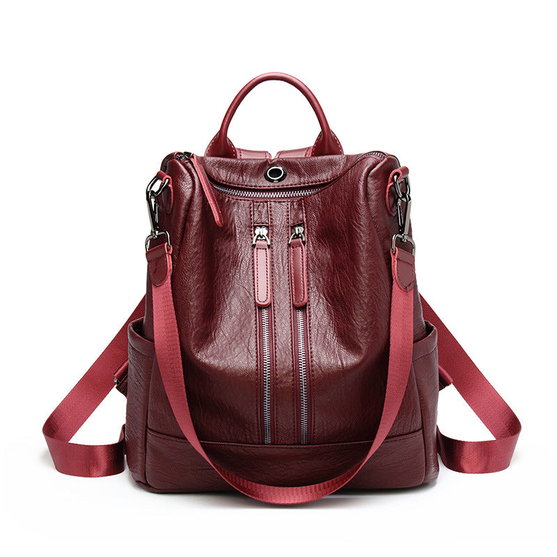 Dark burgundy multifunctional soft leather backpack with vertical zip pockets and adjustable red nylon straps.