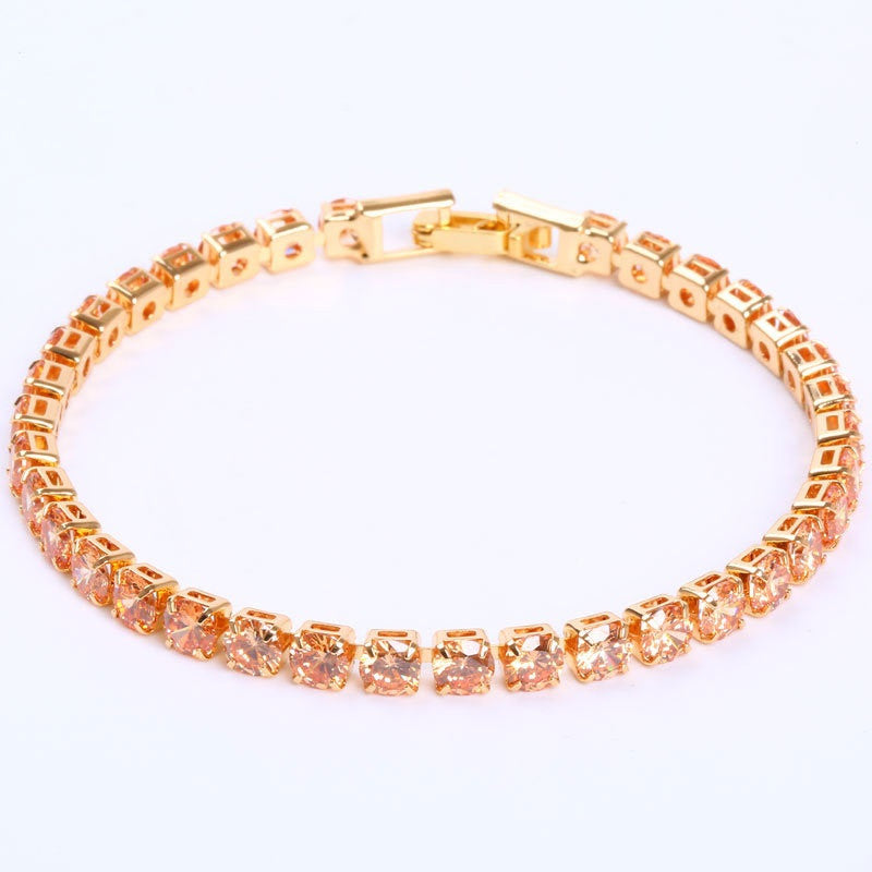Gold-tone tennis bracelet featuring micro-inlaid round orange zircon stones in a classic prong setting.
