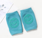 Pair of teal terry cloth baby knee pads with grippy, smiling face icons.