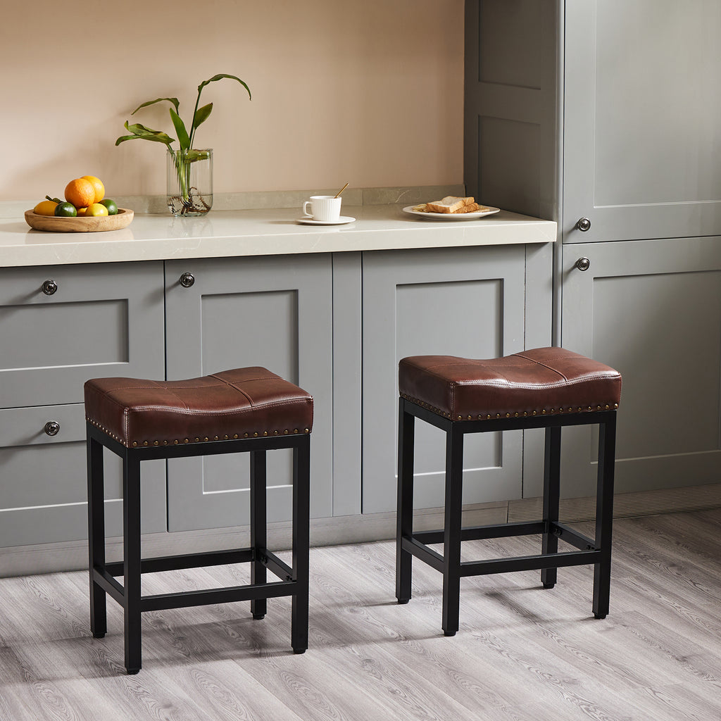 Two saddle-style bar stools with brown faux leather seats and nailhead trim on sturdy black metal frames.