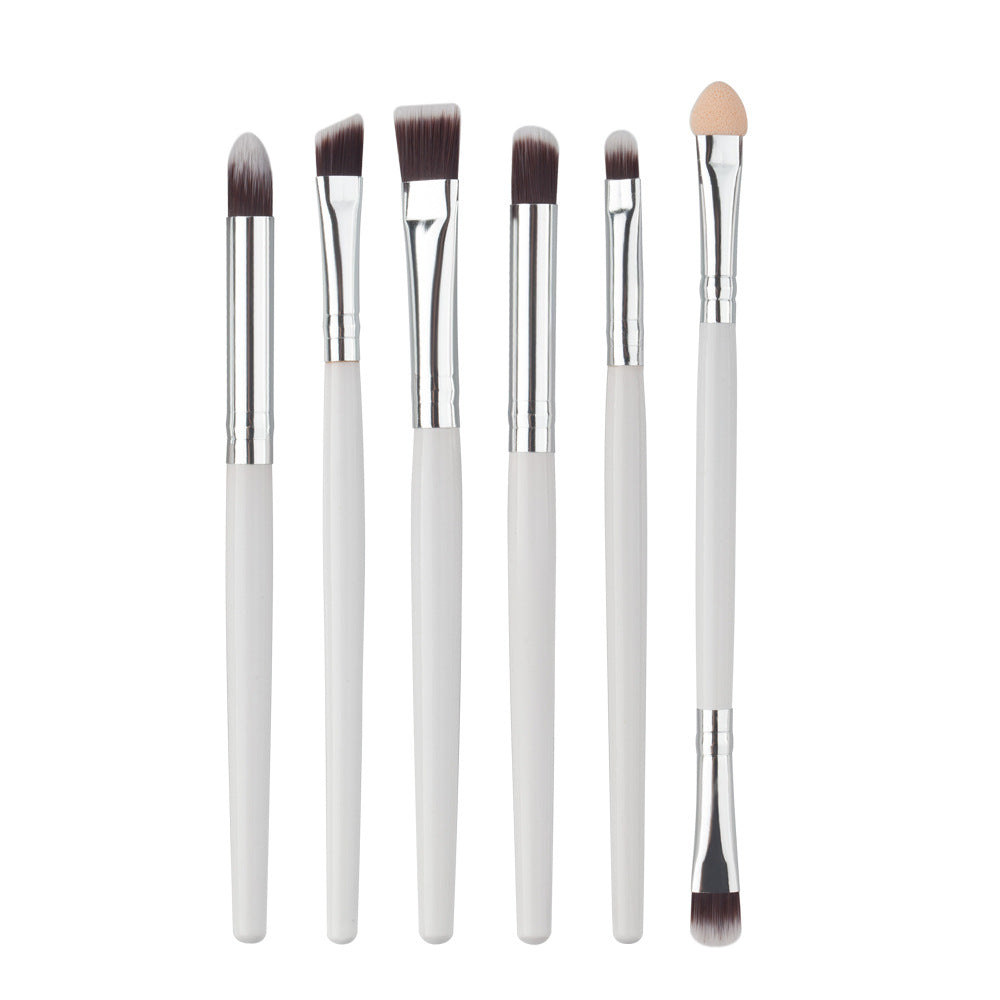 Set of 6 makeup brushes with white handles, silver ferrules, dark synthetic bristles, and one sponge-tip applicator.