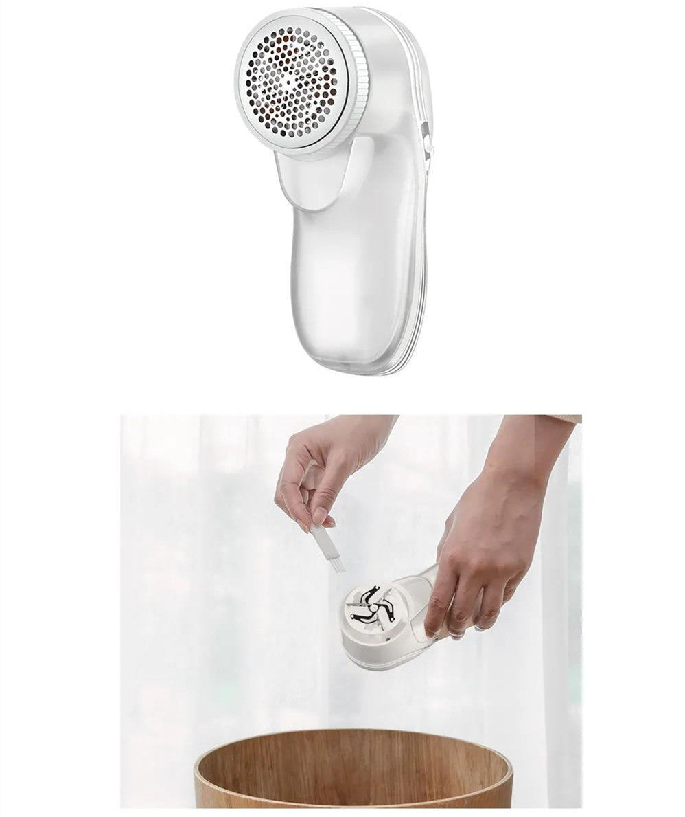White electric lint remover with a metal mesh head, shown being cleaned with a small brush over a wooden bin.