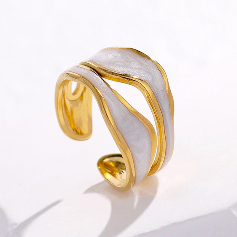Gold-tone titanium steel open-toed ring with a wavy, white enamel inlay on a white background.